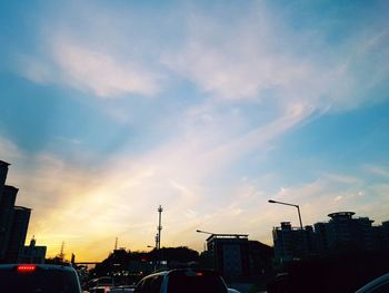 Cars on road in city against sky during sunset