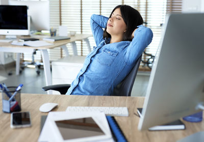 Young woman using phone while sitting on table