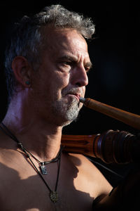 Portrait of man holding cigarette against black background