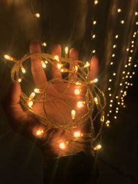 Close-up of hand holding illuminated christmas lights