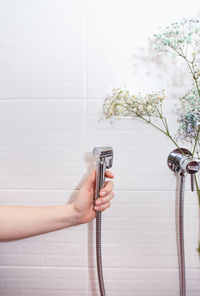 The concept of hygiene and cleanliness. hygienic chrome shower in hand on white tile background