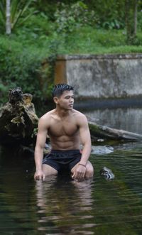 Shirtless man swimming in lake