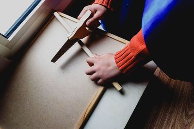 High angle view of person cutting wood at table in workshop