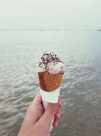 Midsection of person holding ice cream in sea