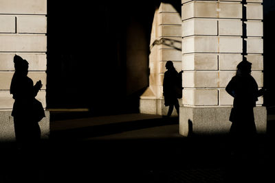 Silhouette people walking in front of historic building