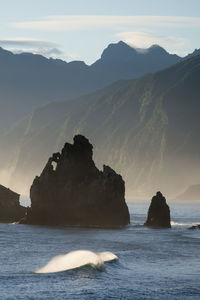 Rocks in sea against sky during sunset