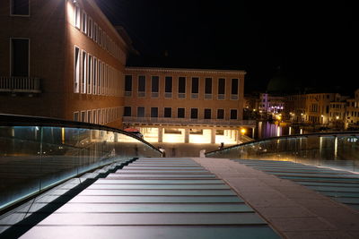 Illuminated street amidst buildings in city at night