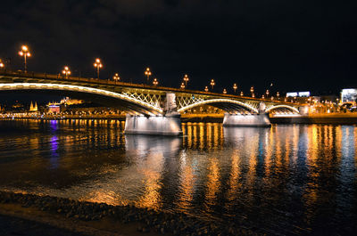 Illuminated bridge over river against sky at night