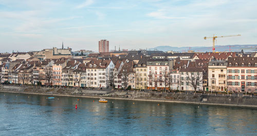 Buildings by river against sky in city