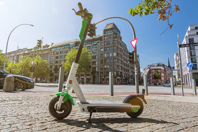 Bicycle by street against buildings in city