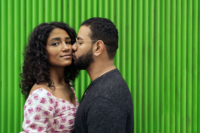 Man kissing woman against wall