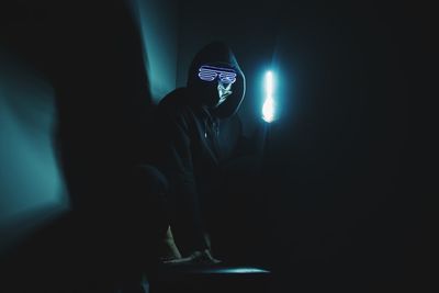 Midsection of man standing in illuminated dark room
