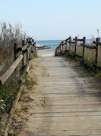 Footpath leading towards sea against clear sky