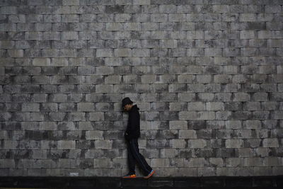 Low section of woman standing against brick wall