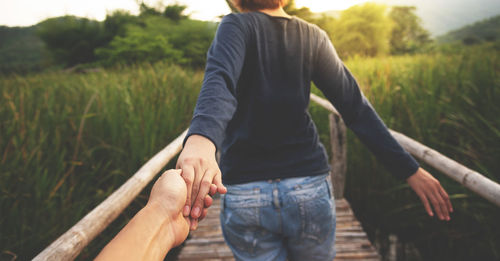 Close-up of woman holding hands of man on footbridge