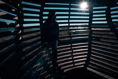 Silhouette of woman with back against lines of shadows