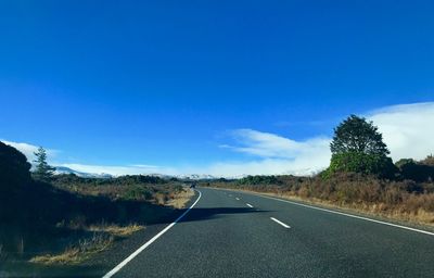 Empty road along trees and blue sky