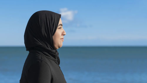 Portrait of young woman standing against sea