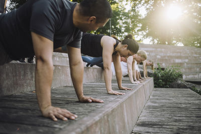 Woman practicing push-ups with friends on steps at park
