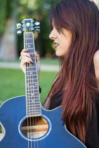 Young woman holding guitar on field