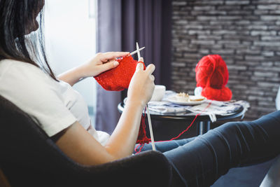 Midsection of woman knitting at home