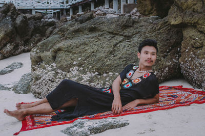 Thoughtful man lying on blanket at beach