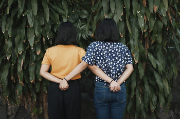 REAR VIEW OF FRIENDS STANDING ON PLANTS OUTDOORS