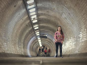 Full length portrait of woman standing in tunnel