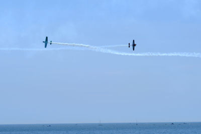 Low angle view of airplane flying over sea against blue sky