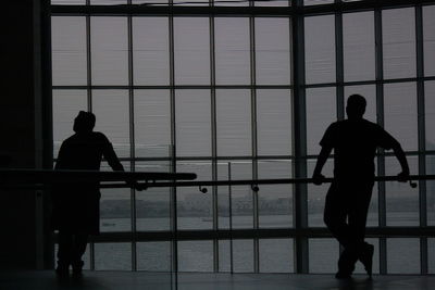 Rear view of silhouette man standing against window