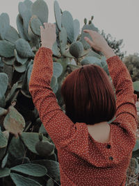 Rear view of woman standing by plants during winter