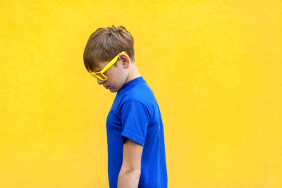 Boy standing against yellow wall