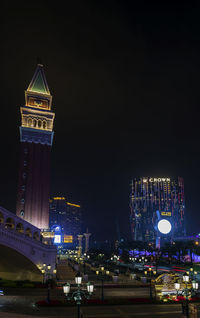 Illuminated buildings in city against clear sky at night