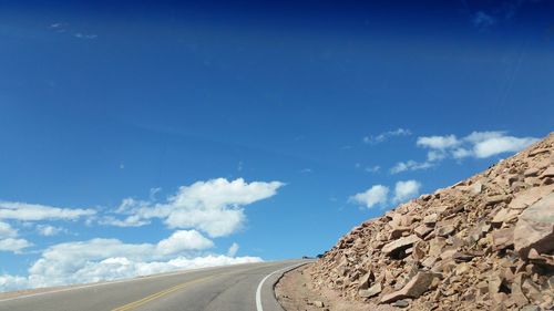 Road amidst mountains against blue sky