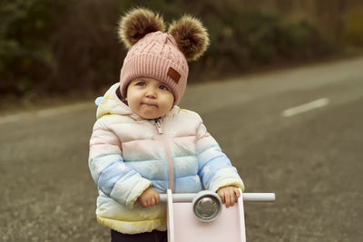 A 1 year old baby girl is with a pink motorcycle outside