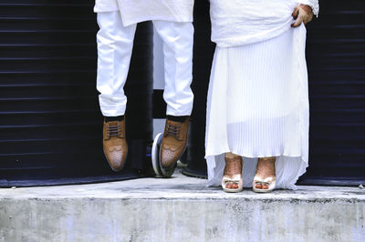 Low section of couple standing on footpath