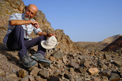 Low angle view of man sitting on rock