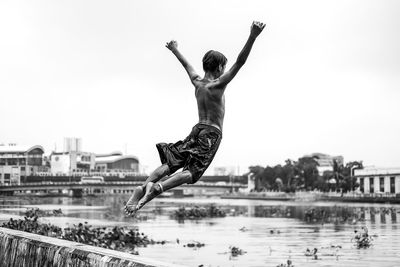 Full length of shirtless man jumping in lake