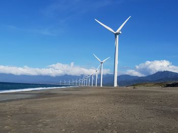 Windmills on beach against sky