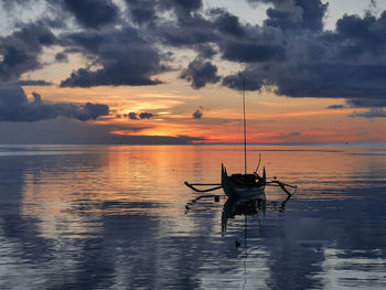 Silhouette boat in sea against sky during sunset