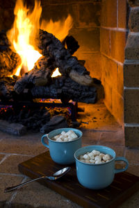 Close-up of marshmallows in cups by fireplace