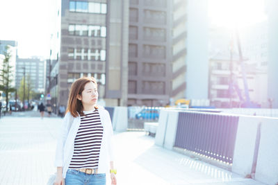 Woman standing on street against buildings in city