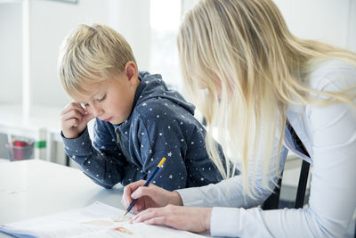 Teacher helping boy in classroom