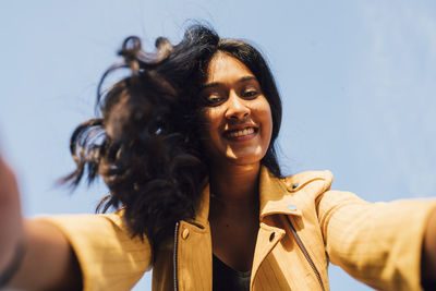 Happy young woman taking selfie on sunny day