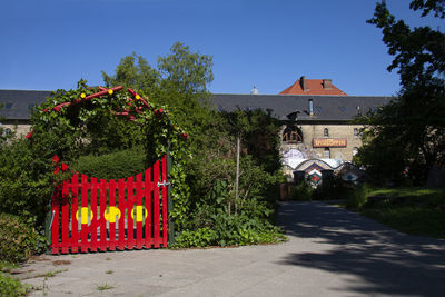 Road by house and buildings against sky