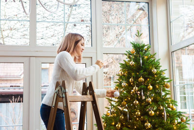 Side view of woman decorating christmas tree