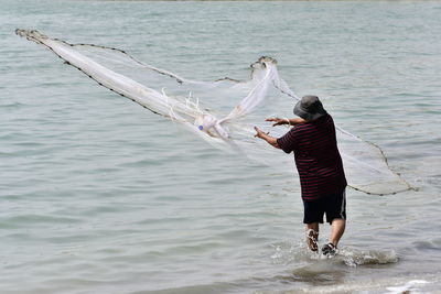 Rear view of woman with arms raised in sea