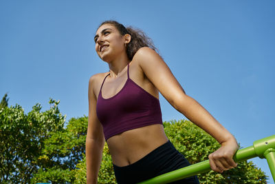 Young woman looking away against blue sky