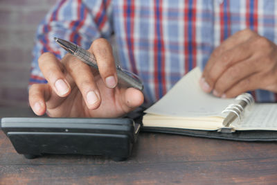 Close-up of man holding cigarette on table