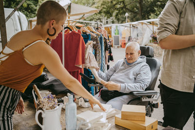 Female customer with disability talking to owner while doing shopping at flea market